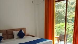 A bedroom with a bed, a chair, and a view of greenery through a window.