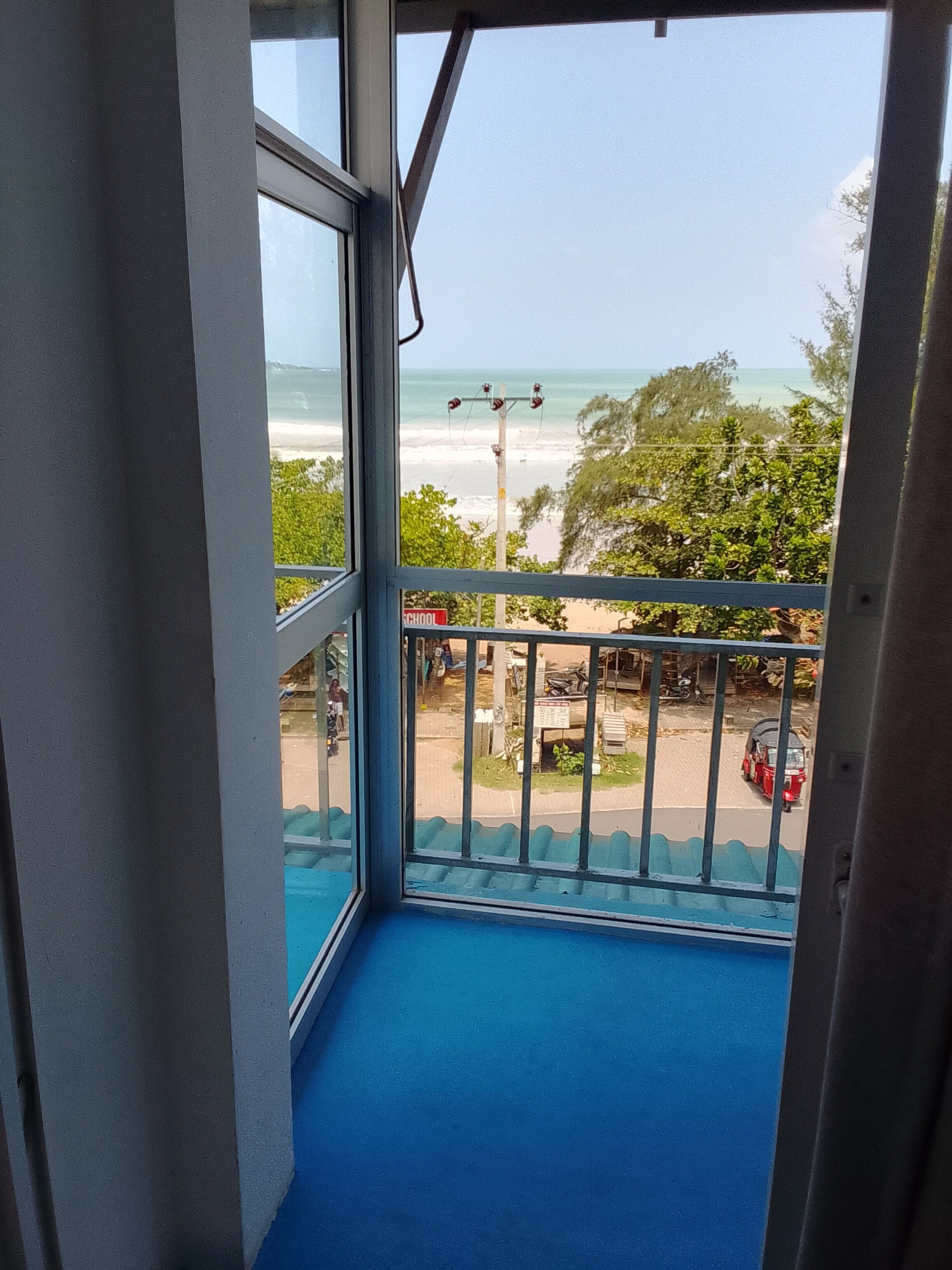 Un balcon avec vue sur la plage et une pancarte sur laquelle on peut lire « ÉCOLE ».