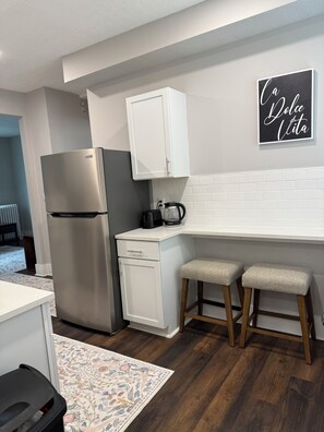A compact kitchen with a stainless steel refrigerator, a coffee maker, and two stools. - Spacious Davenport 3BR/2BA Near Palmer College (Davenport)