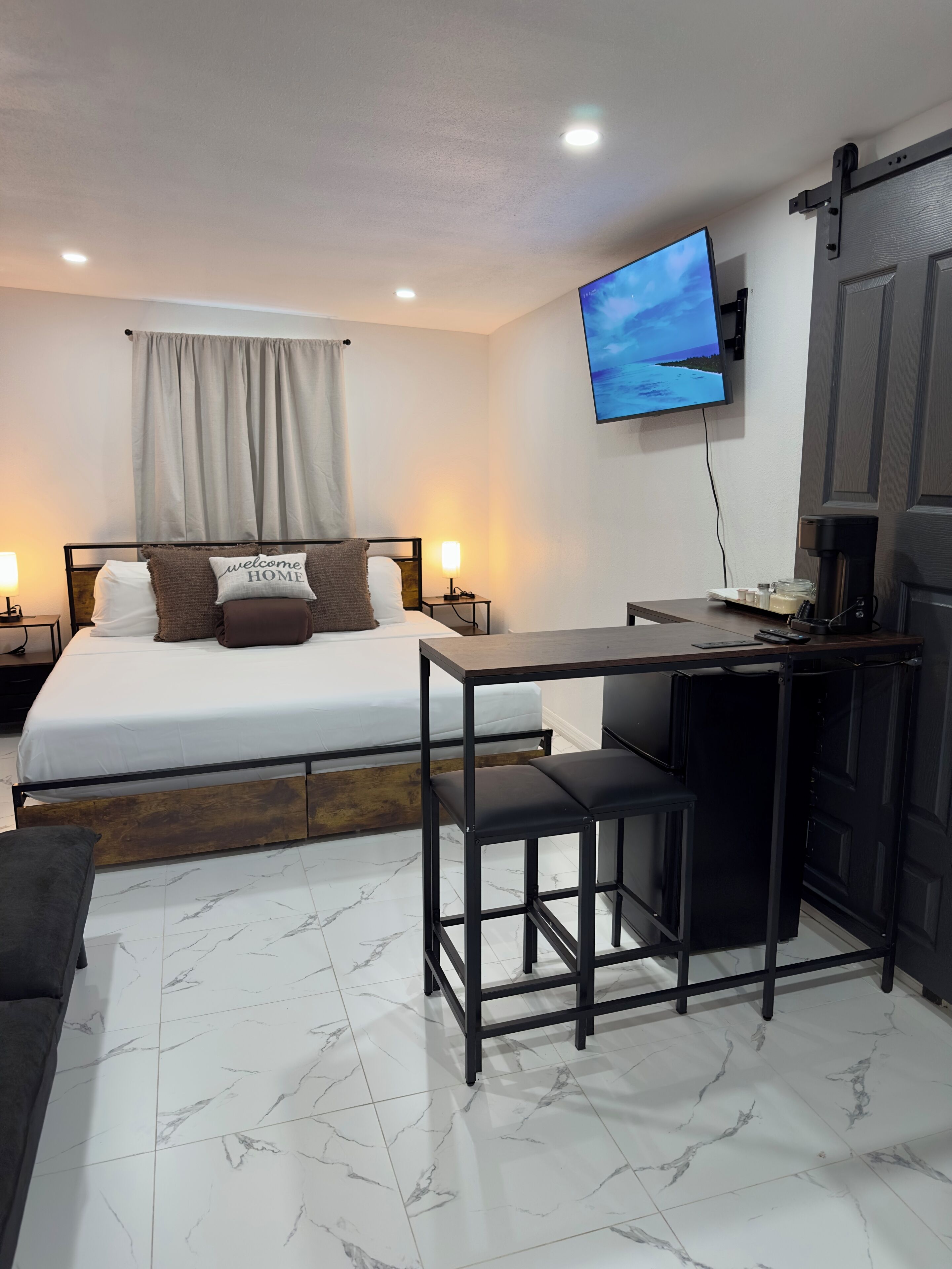 A compact hotel room with a bed, a desk, and a TV mounted on the wall.