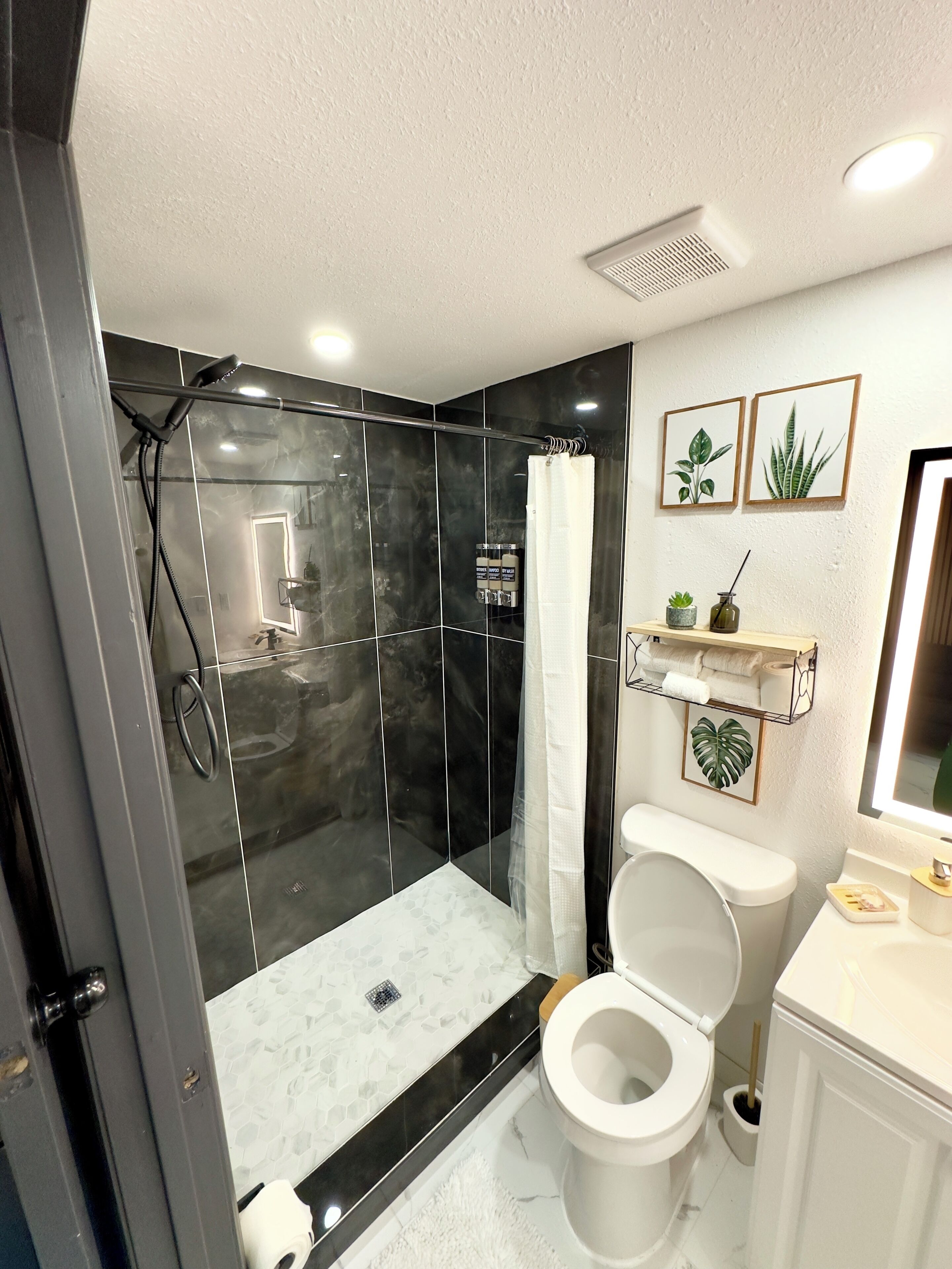 Une salle de bain avec une douche à parois de verre, des toilettes et un lavabo.