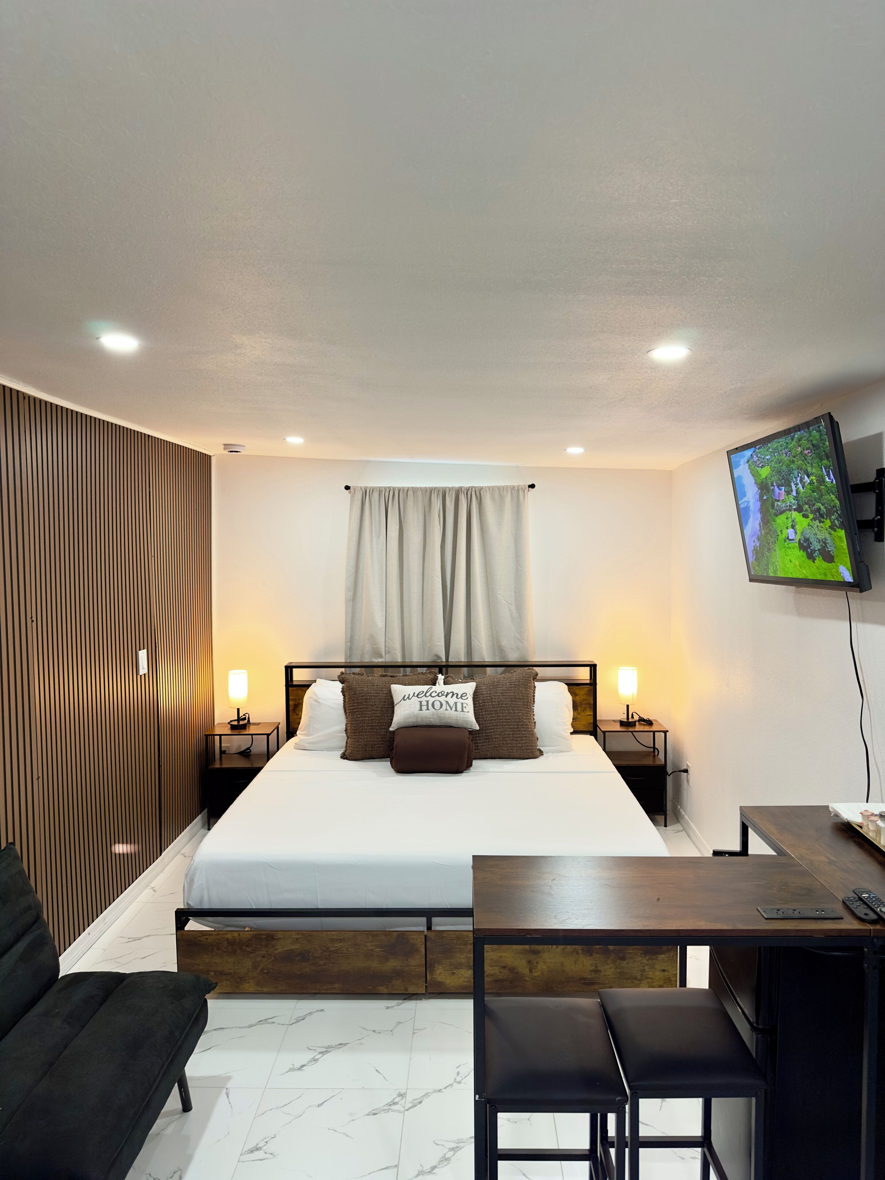 Une chambre d’hôtel comprenant un lit, des tables de chevet, un téléviseur, un bureau et une chaise.