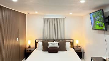 Une chambre d’hôtel comprenant un lit, des tables de chevet, un téléviseur, un bureau et une chaise.