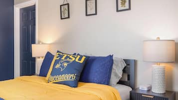 Habitación de hotel con una cama, una mesita de noche, una lámpara y cuadros en la pared.