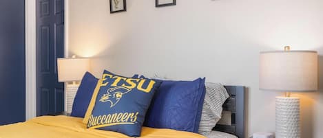 A hotel room with a bed, a nightstand, a lamp, and framed pictures on the wall.