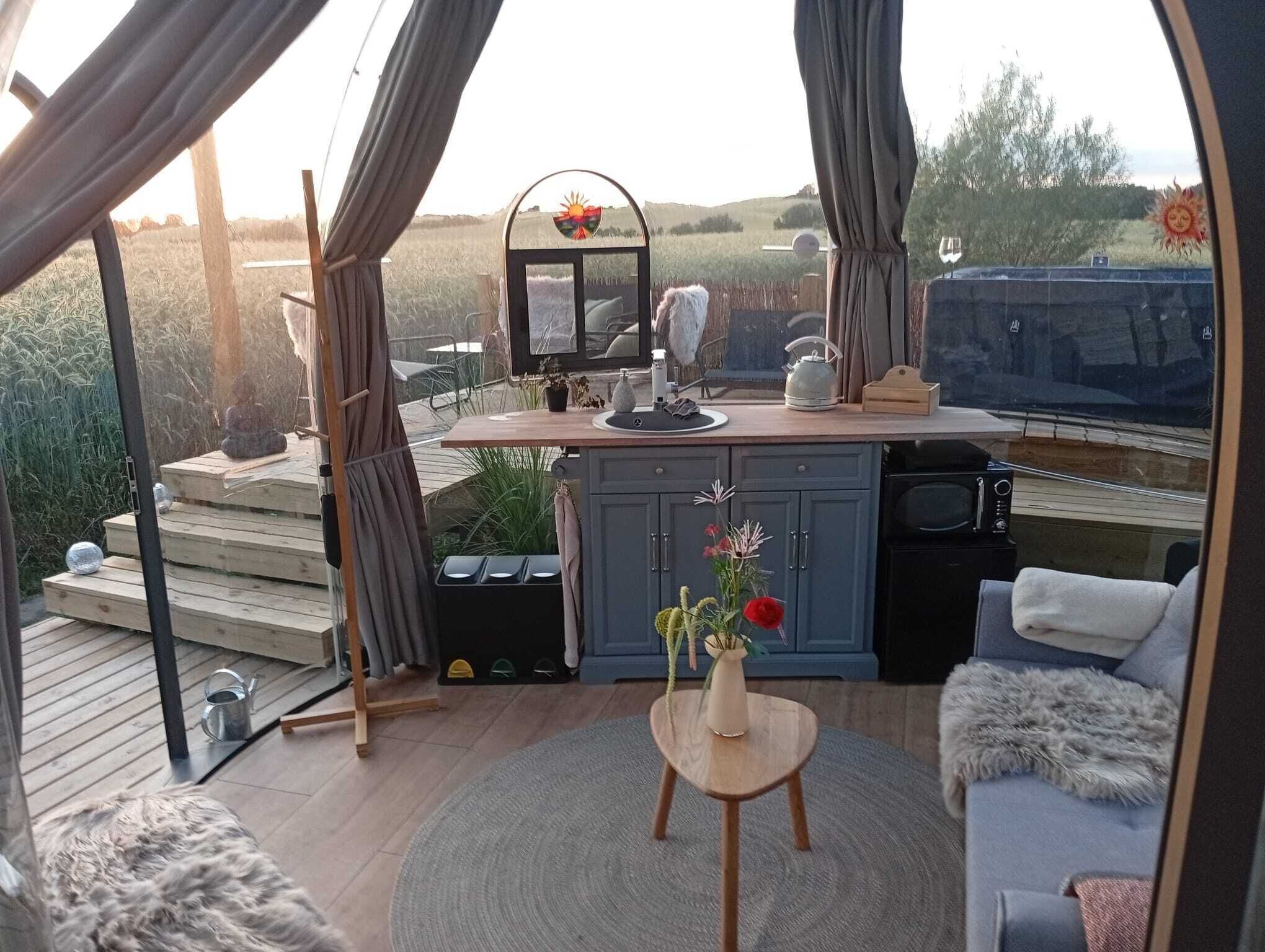 A cozy outdoor living space with a wooden deck, a dining area, and a seating area with a sofa and a small table.