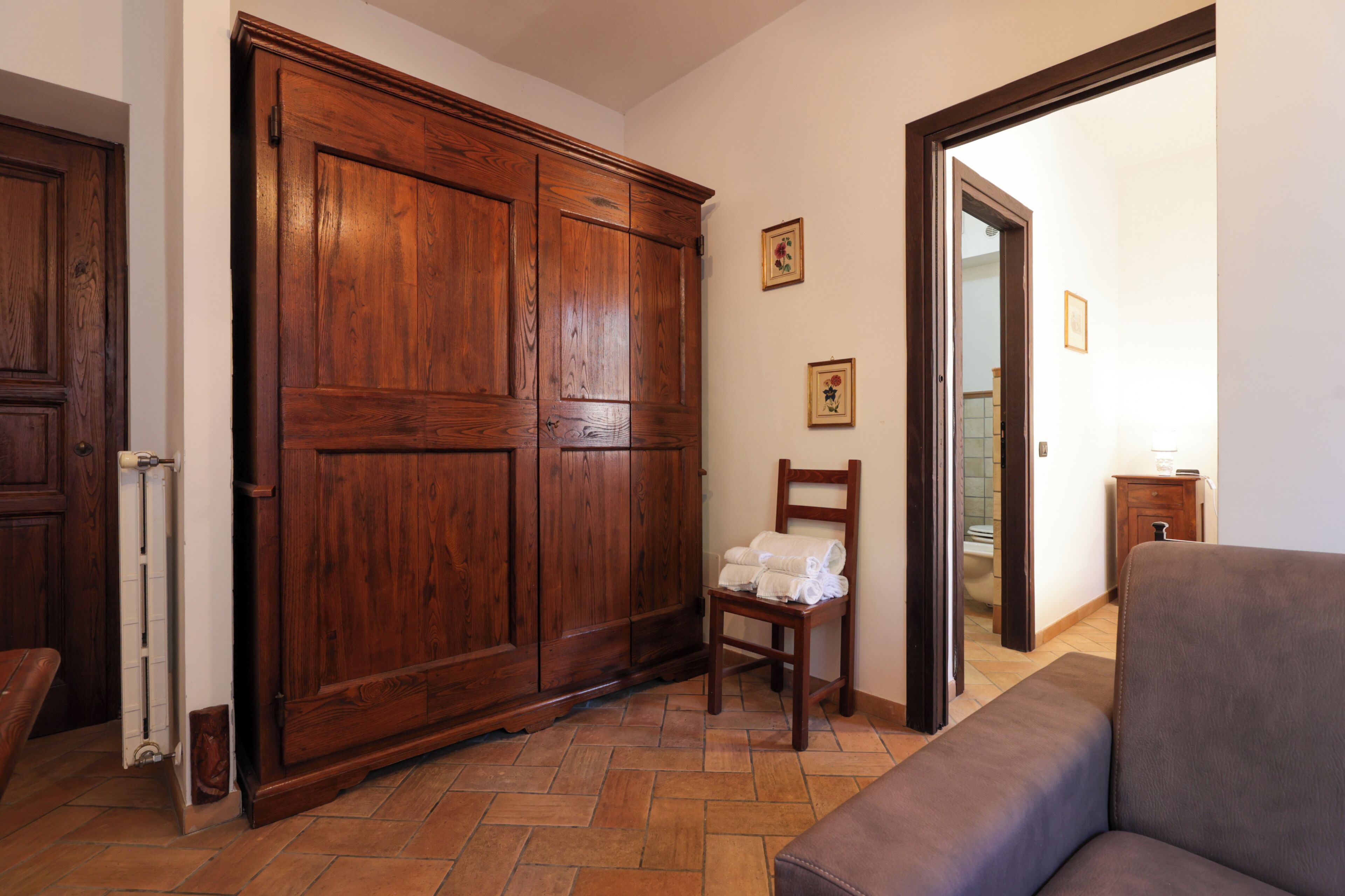 Ein Zimmer mit einem Holzschrank, einem Stuhl mit Handtüchern und einem Sofa.