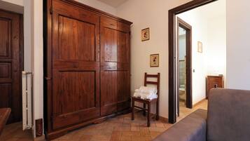 Ein Zimmer mit einem Holzschrank, einem Stuhl mit Handtüchern und einem Sofa.