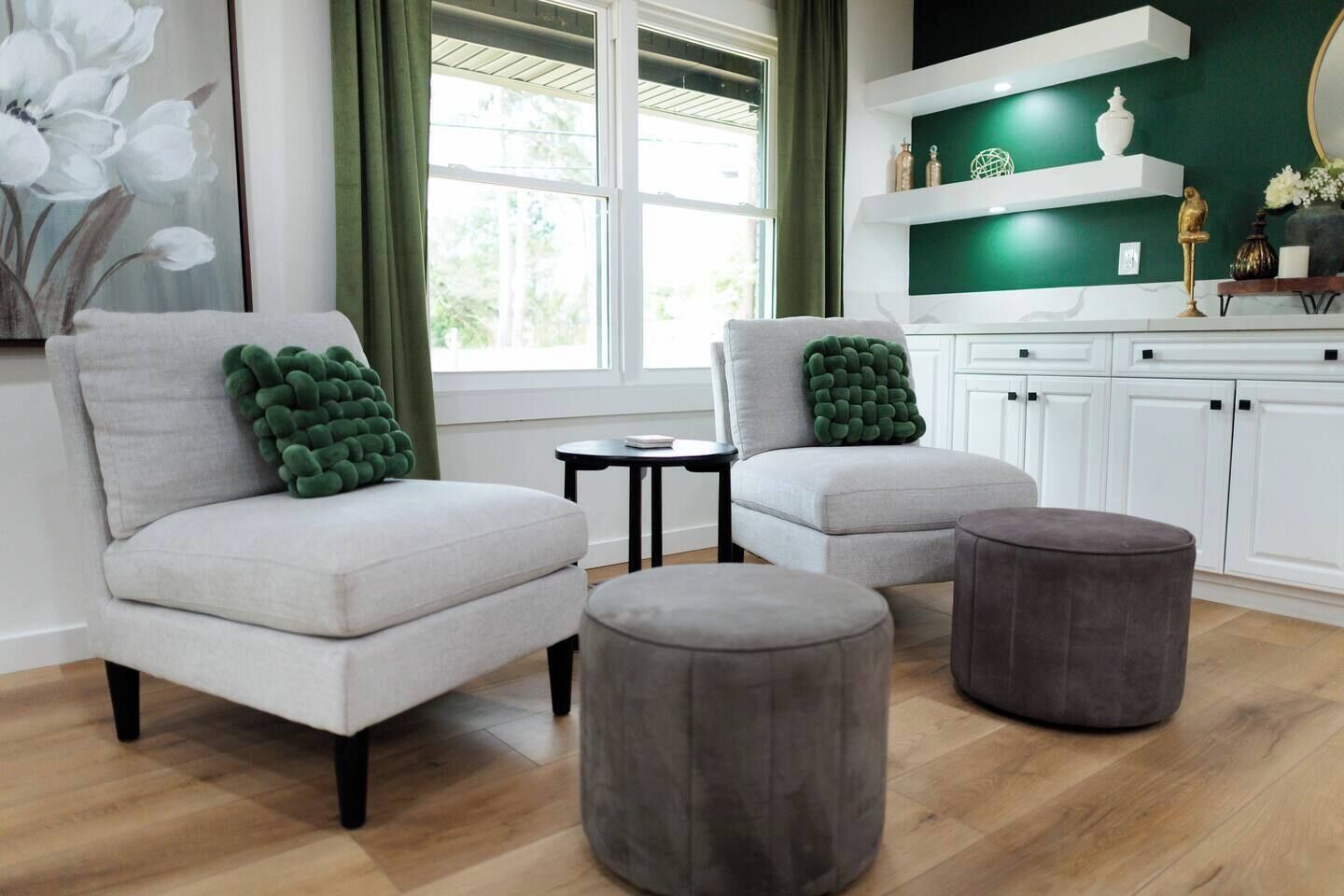 Una sala de estar moderna con dos sillones, una mesita y dos otomanas.