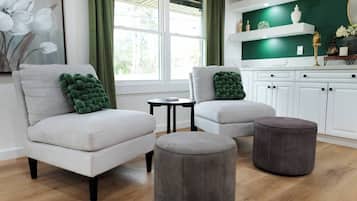 A modern living room with two armchairs, a small table, and two ottomans.