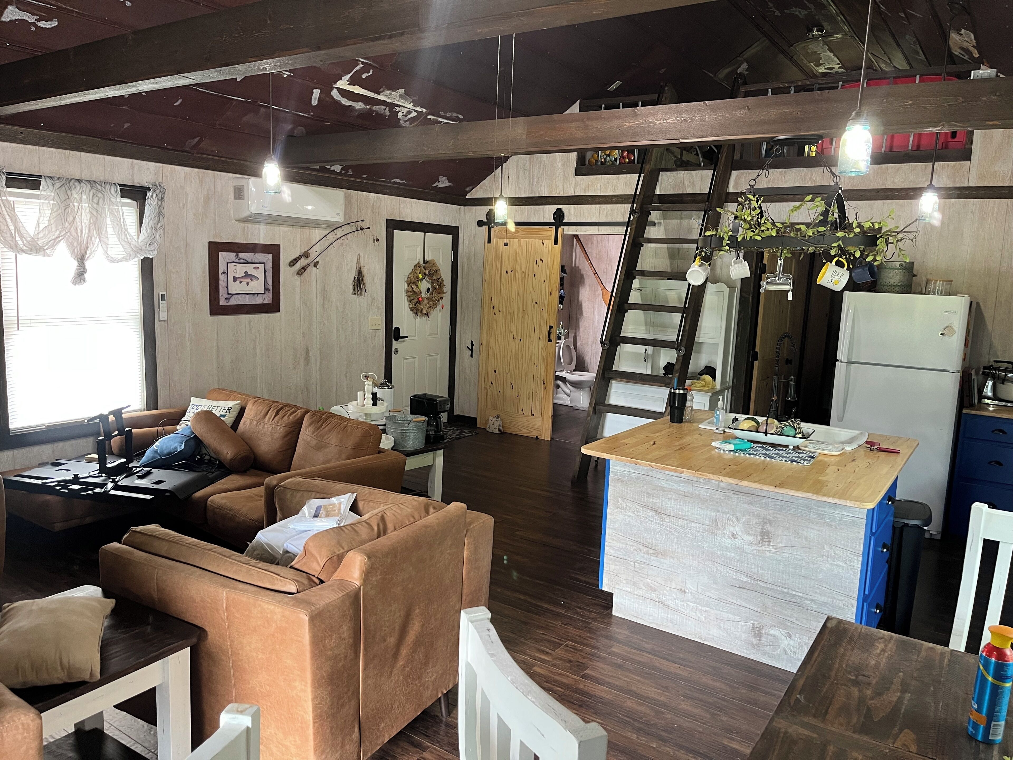 Un espacio de sala cómodo con un sofá, una mesita de centro y una encimera de cocina con refrigerador.