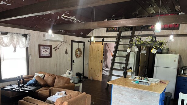 A cozy living area with a sofa, a coffee table, and a kitchen counter with a refrigerator. - Private Cabin on the lake with your own dock. (Decatur)