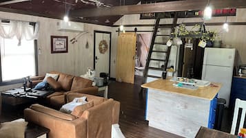 Un espacio de sala cómodo con un sofá, una mesita de centro y una encimera de cocina con refrigerador.