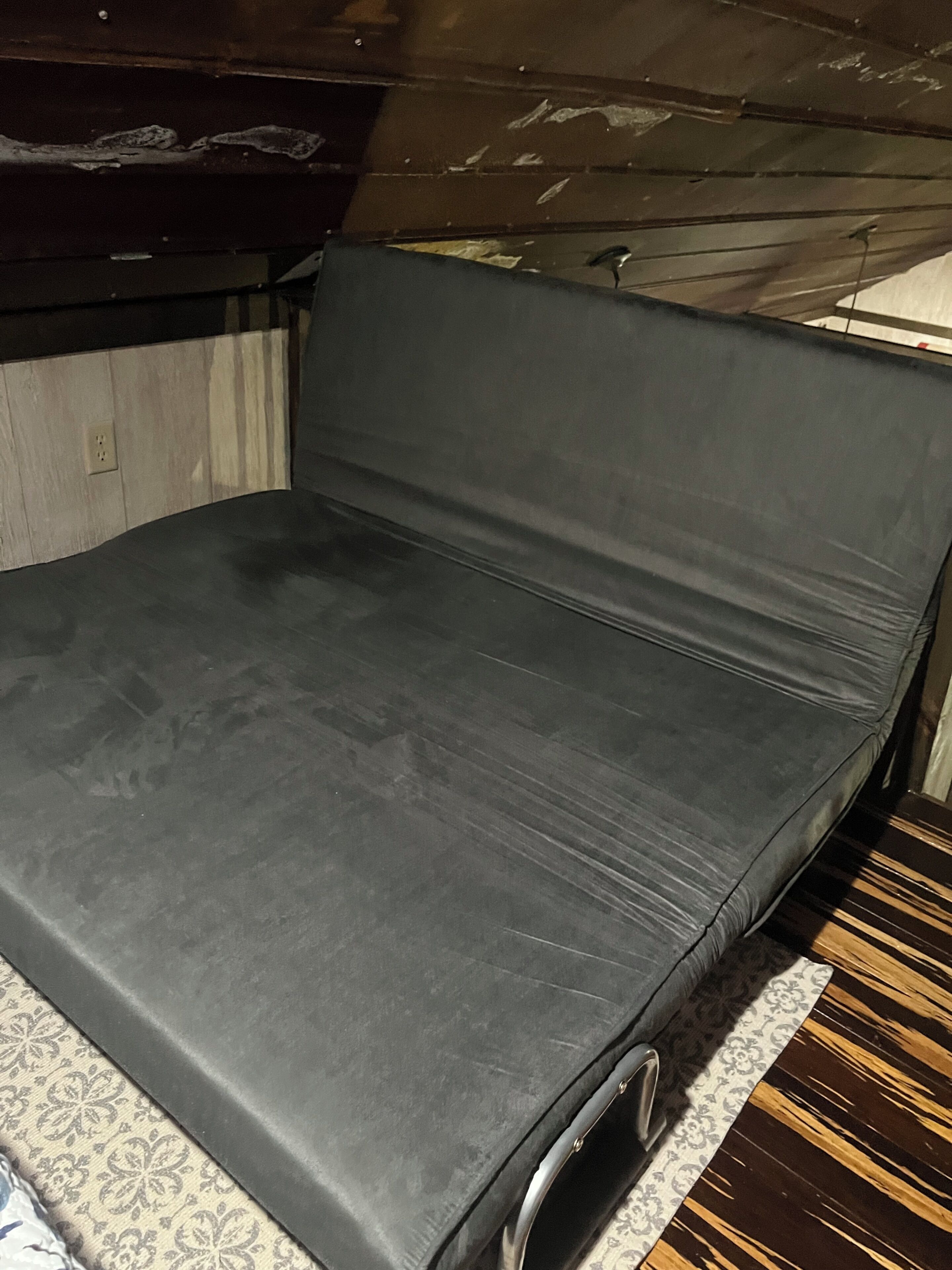Una habitación con una cama, un tapete estampado y suelo de madera.