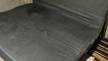 Una habitación con una cama, un tapete estampado y suelo de madera.