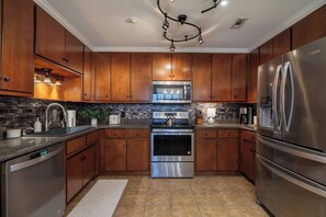 Una cocina moderna con armarios de madera, electrodomésticos de acero inoxidable y salpicadero de azulejos.