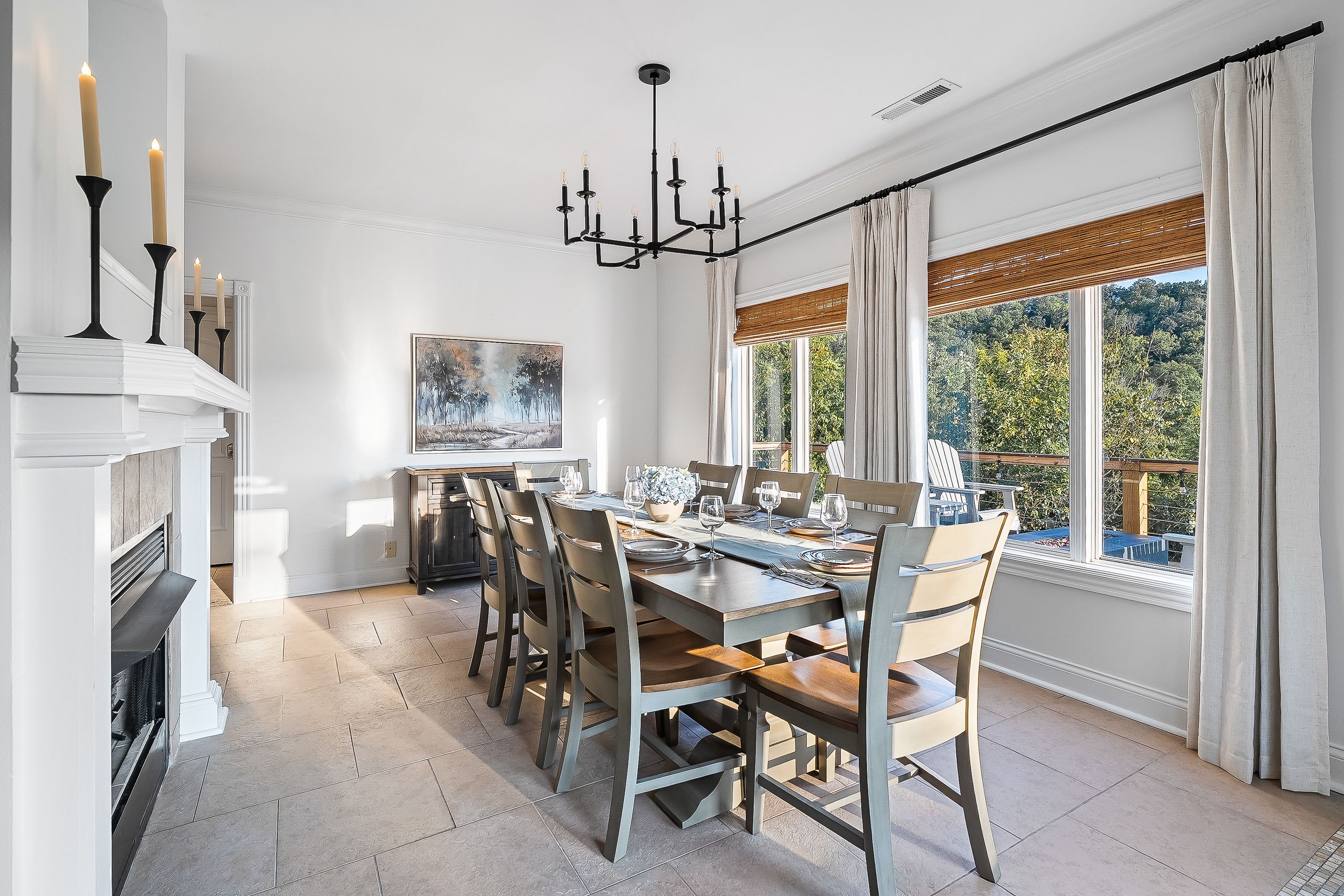 Une salle à manger avec une grande table dressée pour six personnes, une cheminée et une vue sur l’extérieur.