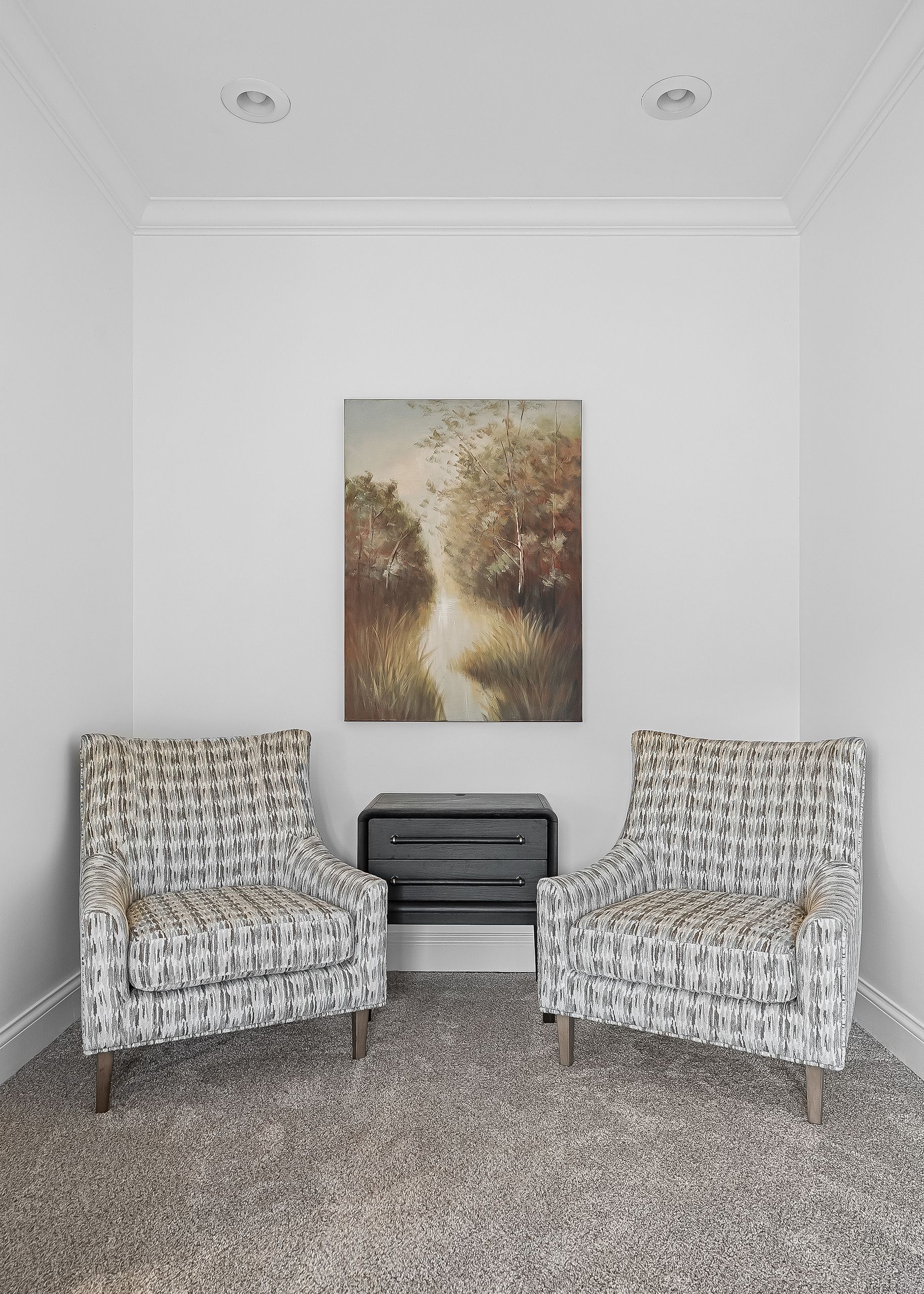 Une pièce comprenant deux fauteuils, un banc et un tableau accroché au mur.