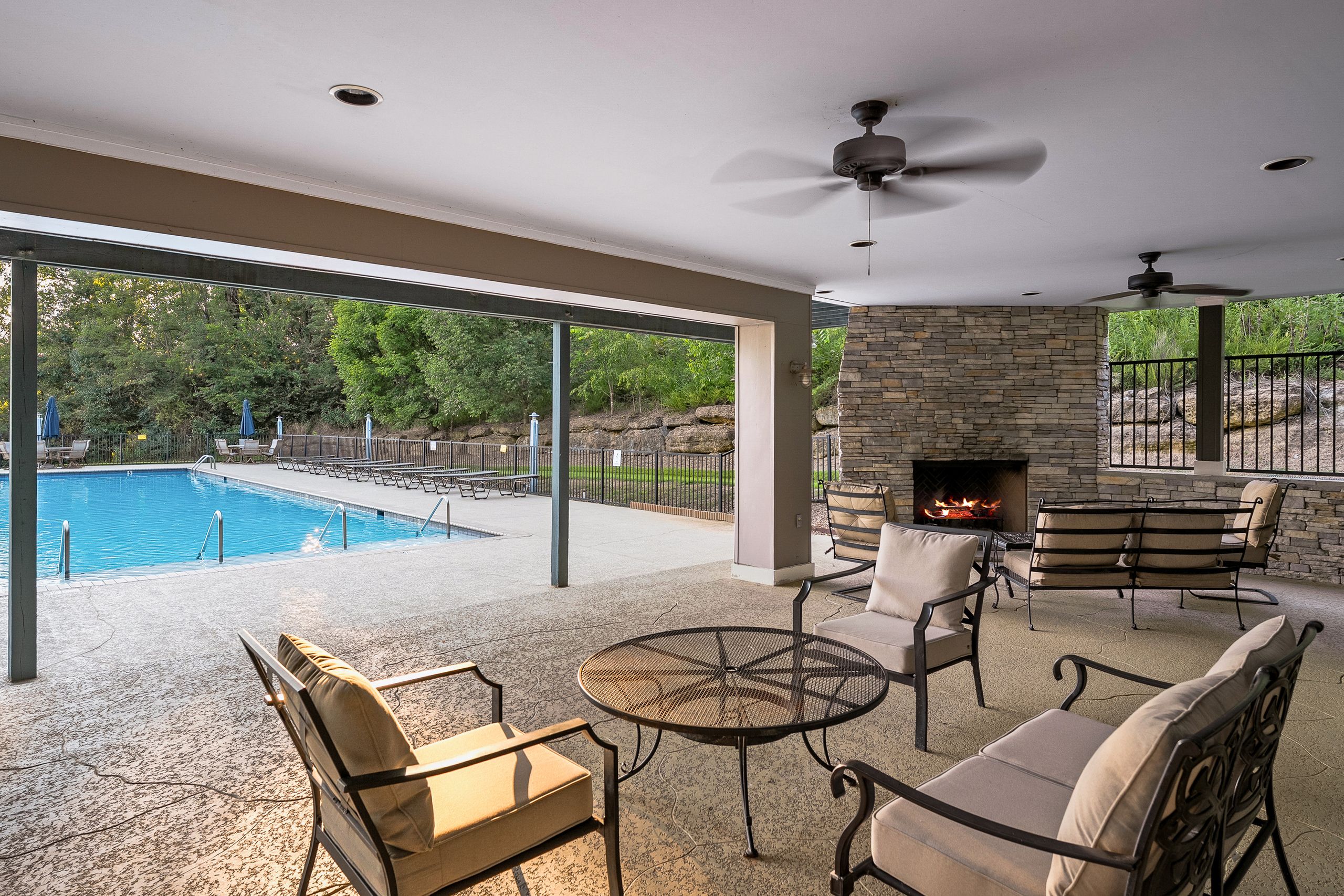 Un patio exterior con piscina, chimenea de piedra y zona de estar.