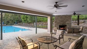 Un patio exterior con piscina, chimenea de piedra y zona de estar.