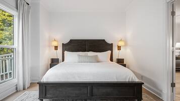 Ein Schlafzimmer mit einem großen Bett, zwei Nachttischlampen, einem dunklen Kopfteil und einem gemusterten Teppich.