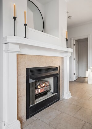 A fireplace with a white mantel, a mirror above it, and two candles.