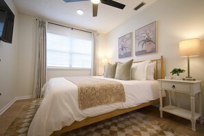 A bedroom with a bed, bedside lamps, a nightstand, and a window with curtains. - Family-Friendly 4 Beds | Central & Fenced Yard (Valdosta)