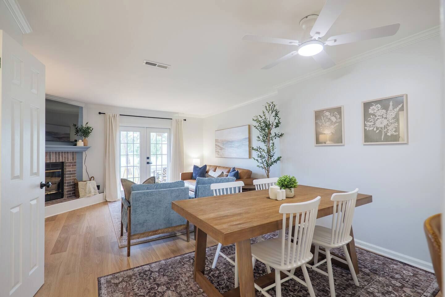 Un coin repas avec une table et des chaises en bois, un ventilateur de plafond et une cheminée.