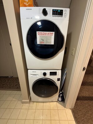 A stacked washer and dryer unit with a moisture sensor and a warning label. - 3 Bedroom Condo with stunning sunset views located in The Homestead Resort! (Glen Arbor)