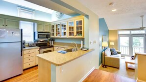 A kitchen with a central island, built-in appliances, and a dining area with a sofa and table. - 3 Bedroom Condo with stunning sunset views located in The Homestead Resort! (Glen Arbor)