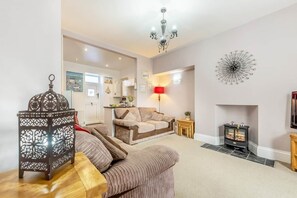 Un salon comprenant un canapé, une lanterne décorative, une cheminée et une horloge murale.