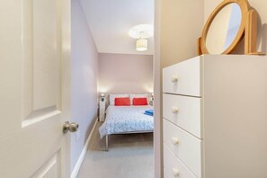 Une chambre à coucher avec un lit, une commode, un miroir et une table de chevet.