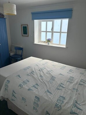 Ein Schlafzimmer mit einem Bett, einem Sessel, einem Fenster mit Blick und einer Heizung.