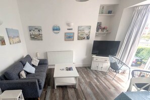 Ein Wohnzimmer mit einer Couch, einem Couchtisch, einem Fernseher und Kunstwerken an den Wänden.