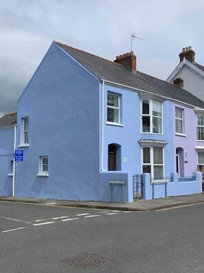 A two-story residential building with a blue facade, a visible front door, and a street sign indicating 'CROFT ROAD.' - Cheriton View | Close to Beach | Sea Glimpse (Tenby)