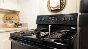 Una cocina con una estufa Whirlpool negra, cuatro hornillas y un panel de control digital.