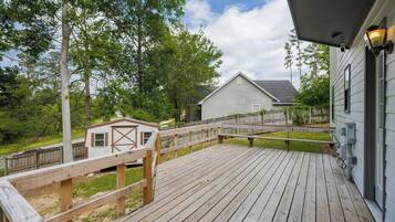 A wooden deck with a small shed and a house in the background.