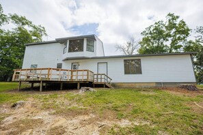 Une maison à deux étages avec une terrasse en bois et un petit escalier menant à la porte d’entrée.