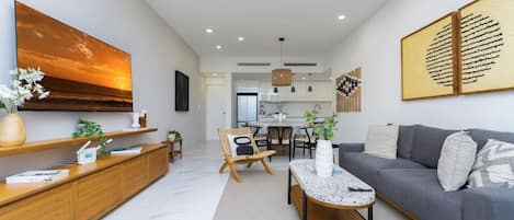 A modern living room with a sofa, coffee table, and a dining area with chairs.