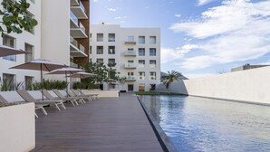 A modern hotel with a poolside area, sun loungers, and umbrellas. - Heart of Cabo|3BR Oasis|Rooftop Spa|Poolside (Cabo San Lucas)
