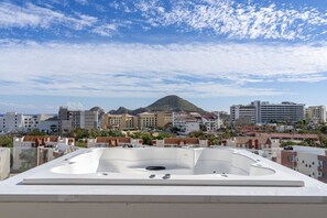 A rooftop pool area with a view of a cityscape and a mountain in the background. - Heart of Cabo|3BR Oasis|Rooftop Spa|Poolside (Cabo San Lucas)