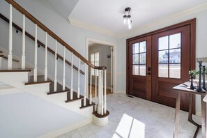 Eine Treppe mit weißen Balustraden und Holzstufen, eine Holztür mit Glasscheiben und ein Marmorboden.