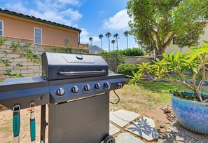 Ein Gasgrill mit Bedienfeld, ein Schlüsselbund und im Hintergrund ein Blumentopf.