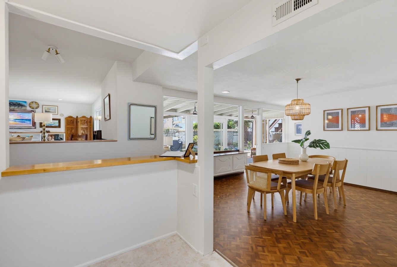 A spacious room with a wooden dining table, chairs, and a hanging light fixture.
