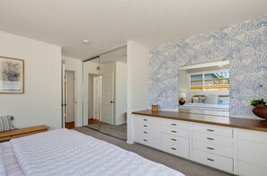 Ein Schlafzimmer mit Bett, Schminktisch, Spiegel und Fenster mit Aussicht.