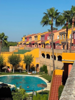 A resort with a swimming pool, colorful buildings, and palm trees.