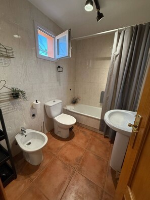 A bathroom with a toilet, bidet, bathtub, and two sinks.