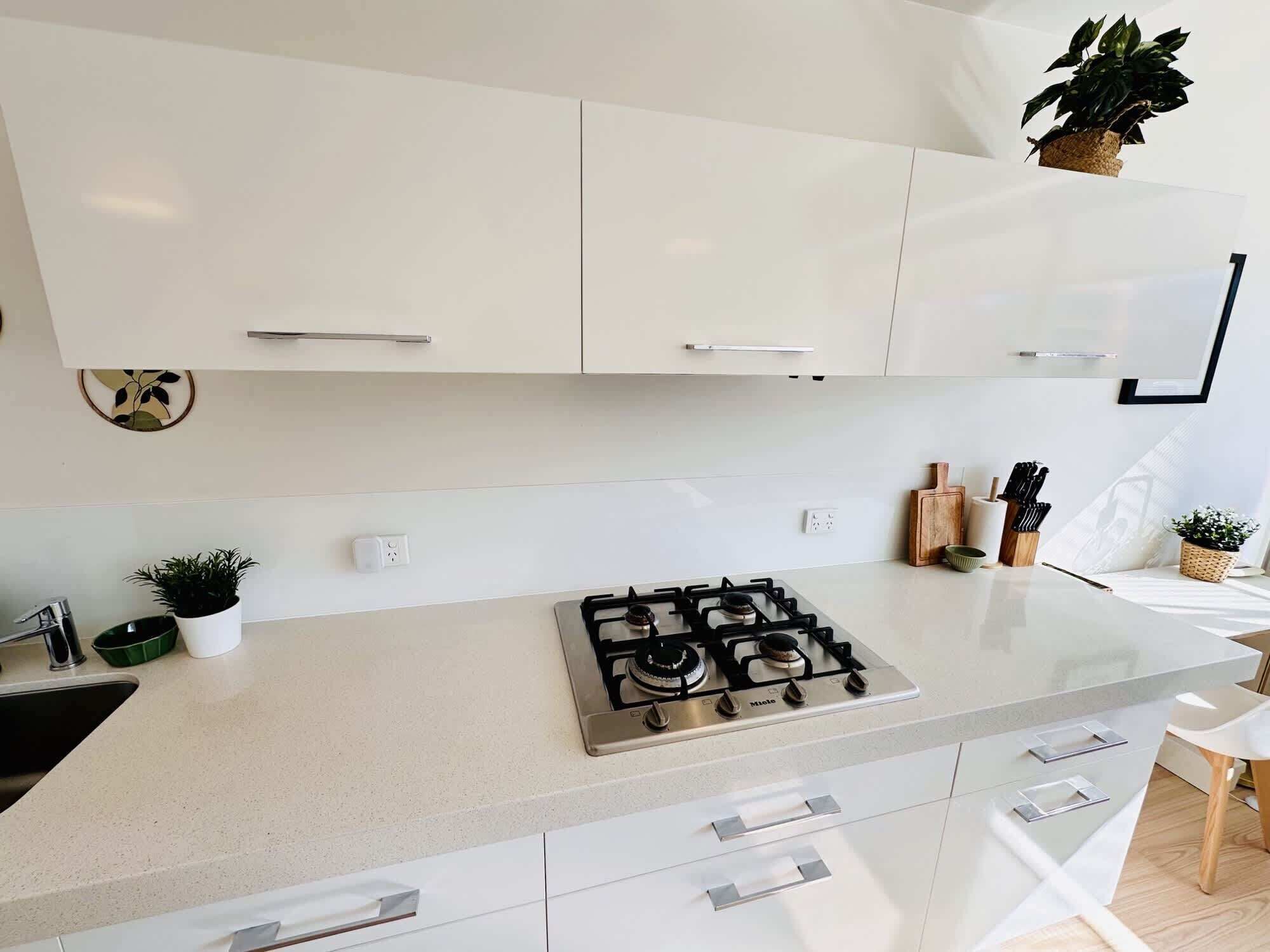 Une cuisine moderne avec des meubles blancs, une cuisinière à gaz et un plan de travail.