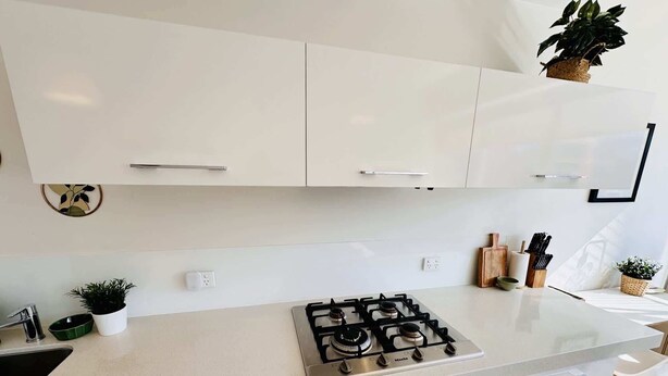 A modern kitchen with white cabinets, a gas stove, and a countertop. - Stylish 1-Bed Apartment in Adelaide CBD (Adelaide)