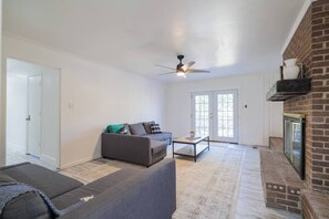 A living room with a sofa, a coffee table, and a ceiling fan. - Sleeps 18 Riverfront Getaway with Game Room & Deck (Valdosta)